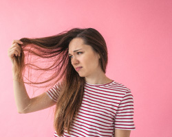 A woman looks at her long brown hair.